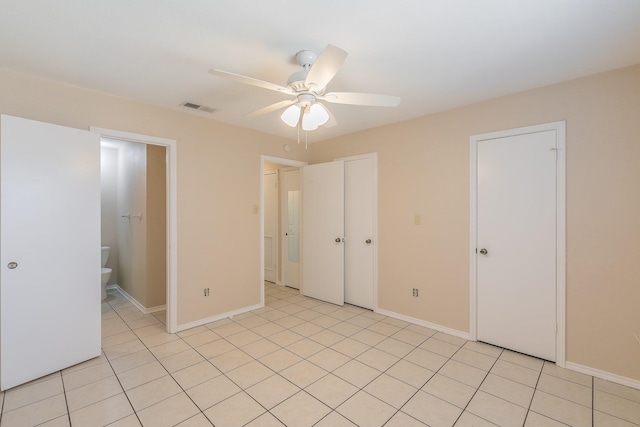 unfurnished bedroom with ceiling fan, light tile patterned floors, and ensuite bath