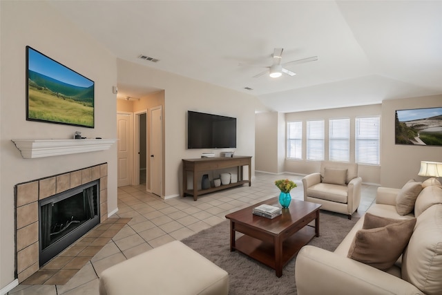 tiled living room with ceiling fan and a tile fireplace