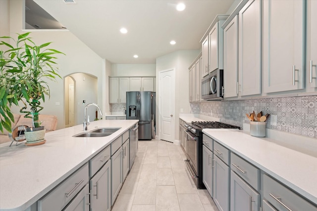 kitchen with sink, gray cabinetry, light tile patterned floors, stainless steel appliances, and decorative backsplash