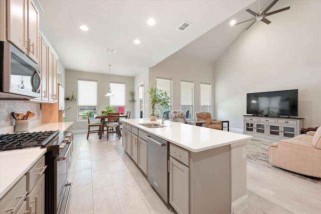 kitchen featuring sink, an island with sink, tasteful backsplash, decorative light fixtures, and stainless steel appliances