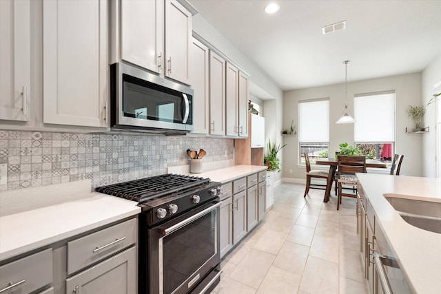 kitchen featuring gray cabinetry, light tile patterned floors, range with gas cooktop, and decorative light fixtures