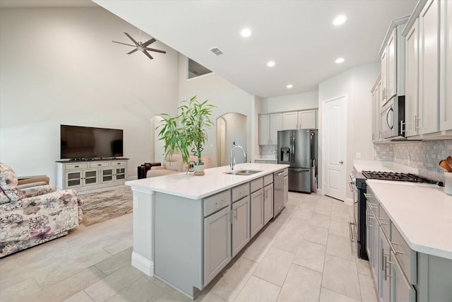 kitchen with sink, ceiling fan, an island with sink, tasteful backsplash, and stainless steel appliances