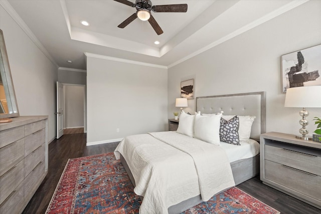 bedroom featuring dark hardwood / wood-style flooring, a tray ceiling, crown molding, and ceiling fan