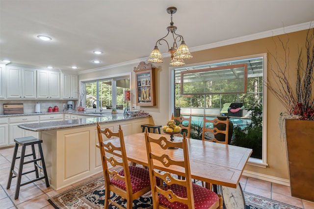 dining room with crown molding, light tile patterned floors, sink, and an inviting chandelier