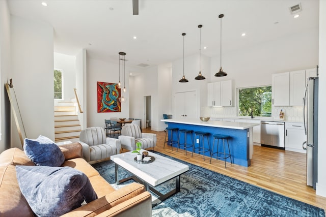 living room featuring a towering ceiling and light hardwood / wood-style flooring