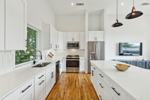 kitchen featuring white cabinets, light hardwood / wood-style floors, backsplash, stainless steel appliances, and sink