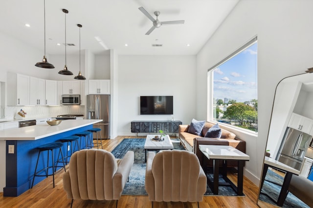 living room featuring light hardwood / wood-style flooring, ceiling fan, and a wealth of natural light