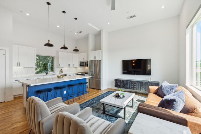 living room with light wood-type flooring, sink, and a high ceiling