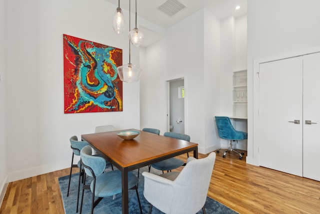 dining space featuring a towering ceiling and light hardwood / wood-style floors