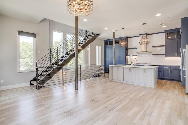 kitchen with backsplash, light hardwood / wood-style flooring, and a center island with sink