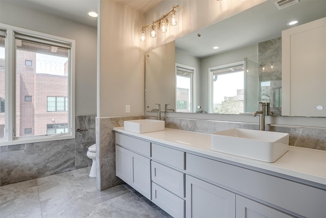 bathroom with vanity, tile walls, a wealth of natural light, and toilet