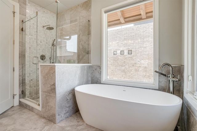 bathroom featuring shower with separate bathtub, tile walls, and tile patterned flooring