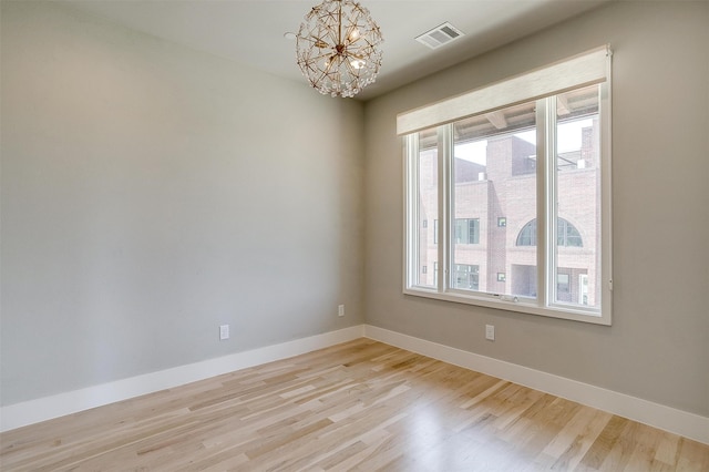 empty room with an inviting chandelier and light hardwood / wood-style floors