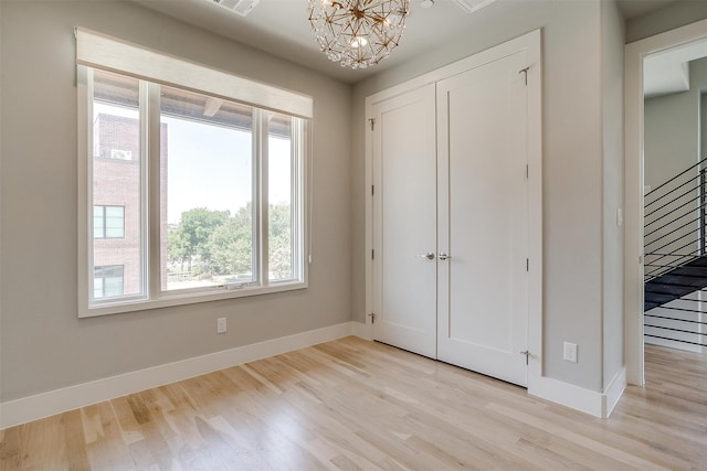 unfurnished bedroom with light wood-type flooring and an inviting chandelier