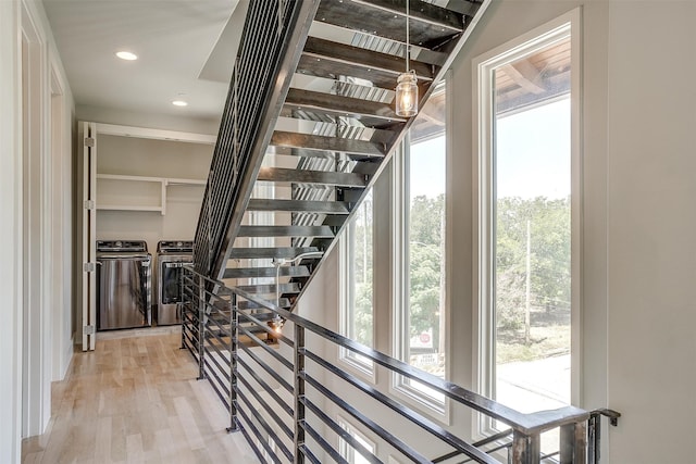 stairway with washing machine and clothes dryer and hardwood / wood-style floors