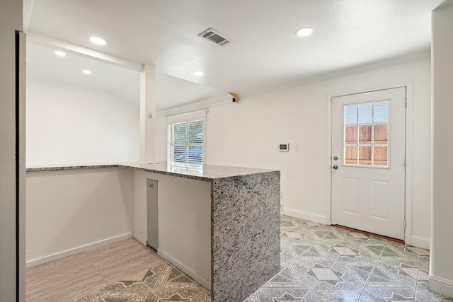 kitchen featuring kitchen peninsula, stone counters, and a wealth of natural light