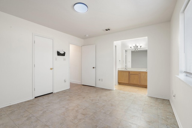 unfurnished bedroom with a chandelier and ensuite bathroom