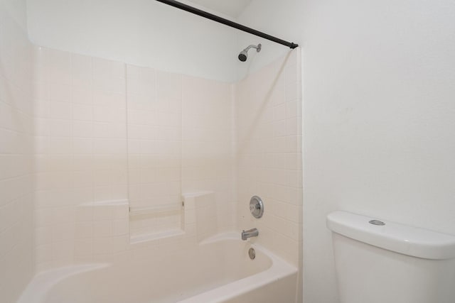 bathroom featuring toilet and tiled shower / bath