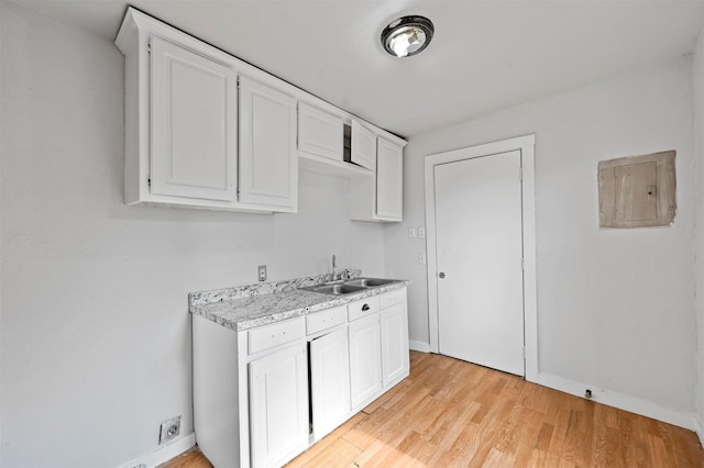 kitchen with white cabinets, light wood-type flooring, and sink