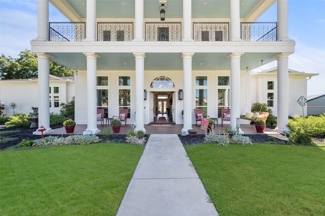 view of exterior entry featuring a lawn and a balcony