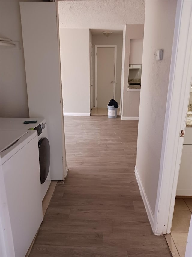 clothes washing area featuring wood-type flooring, washer and clothes dryer, and a textured ceiling