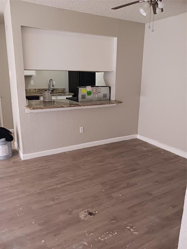 interior space featuring ceiling fan, wood-type flooring, and a textured ceiling