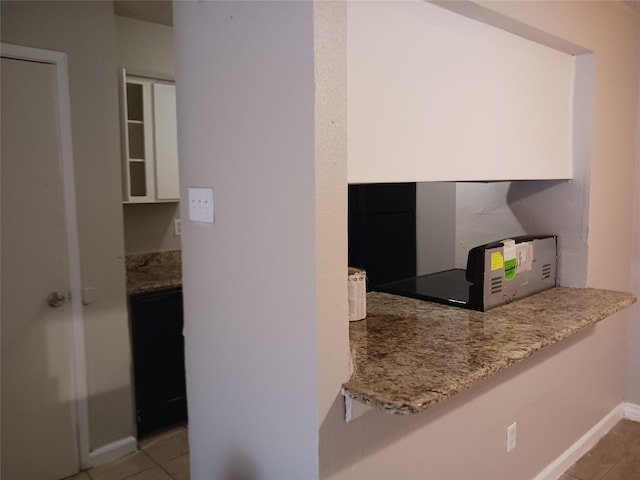 kitchen with light tile patterned flooring, white cabinets, and light stone counters