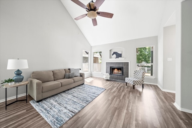 living room with ceiling fan, a tiled fireplace, high vaulted ceiling, and dark hardwood / wood-style flooring