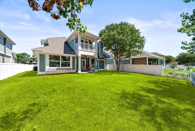 rear view of house featuring a yard and a balcony