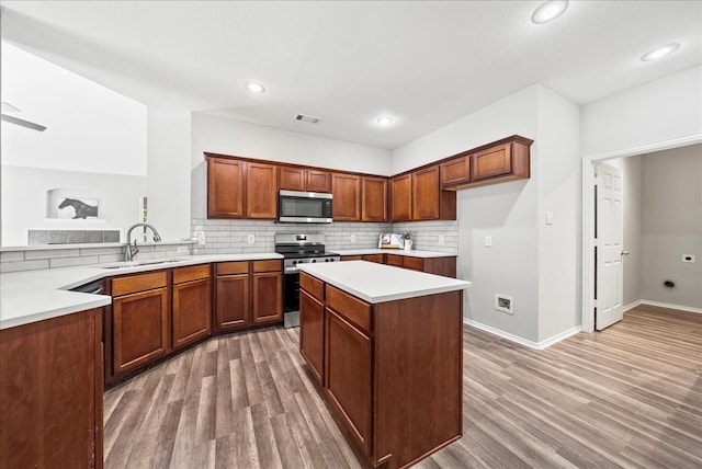 kitchen featuring backsplash, a center island, light hardwood / wood-style flooring, stainless steel appliances, and sink