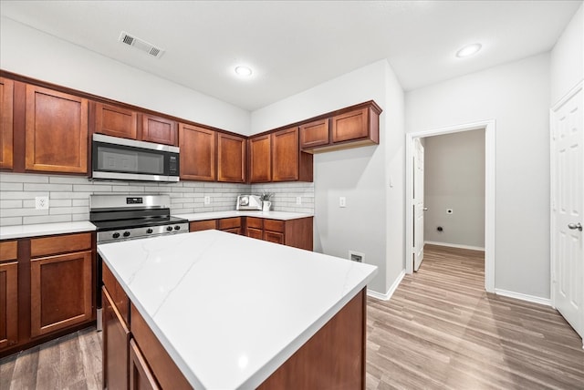 kitchen featuring a kitchen island, stainless steel appliances, decorative backsplash, and hardwood / wood-style flooring