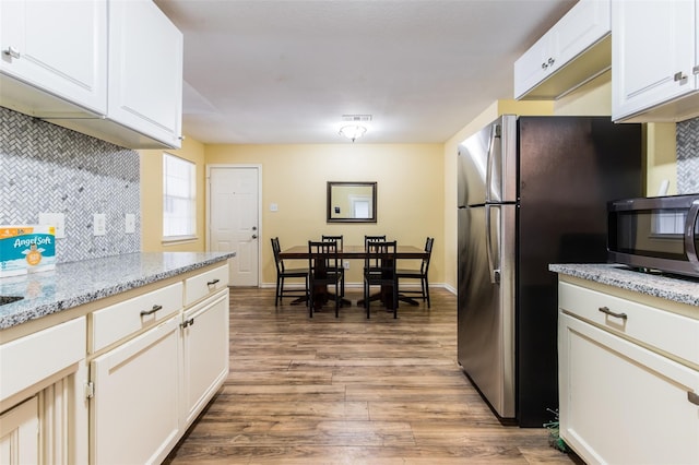 kitchen featuring tasteful backsplash, stainless steel appliances, light hardwood / wood-style floors, white cabinetry, and light stone counters