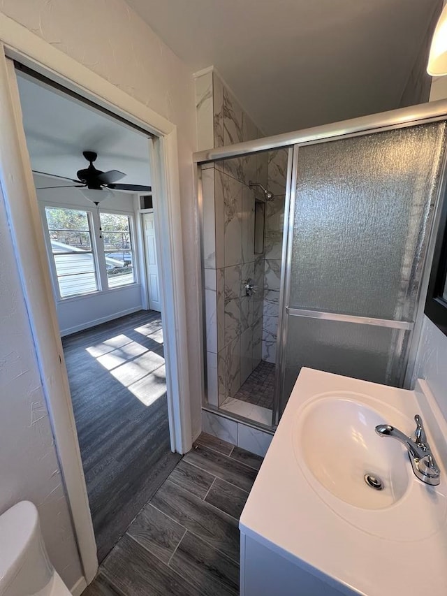 bathroom featuring hardwood / wood-style floors, ceiling fan, toilet, vanity, and walk in shower