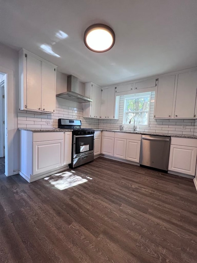 kitchen with dark hardwood / wood-style floors, white cabinets, wall chimney range hood, and stainless steel appliances