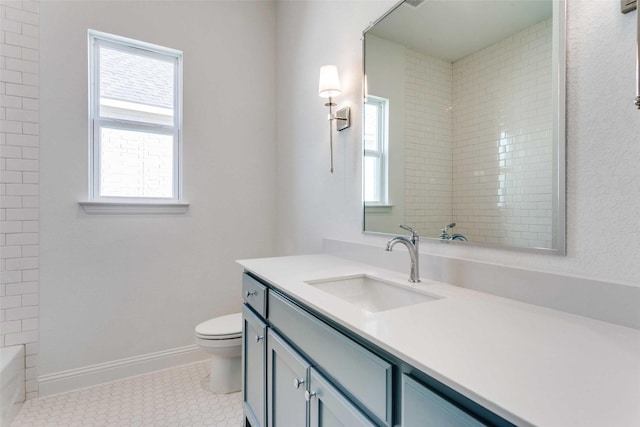 bathroom featuring toilet, plenty of natural light, baseboards, and vanity