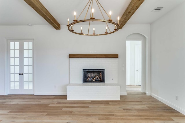 unfurnished living room featuring french doors, visible vents, light wood-style floors, a brick fireplace, and beamed ceiling