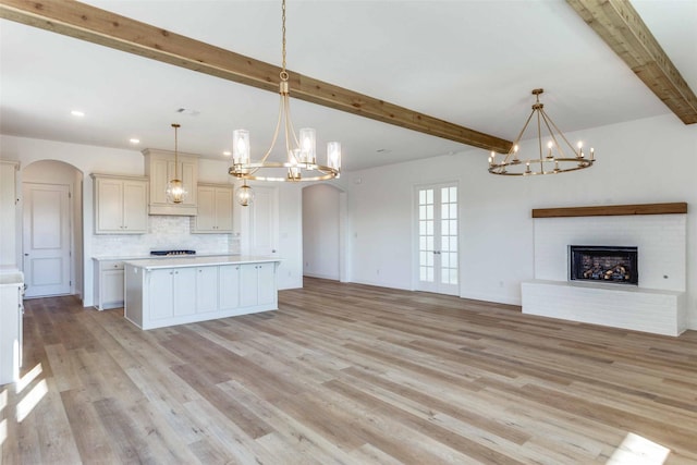 kitchen with arched walkways, a fireplace, tasteful backsplash, light countertops, and open floor plan