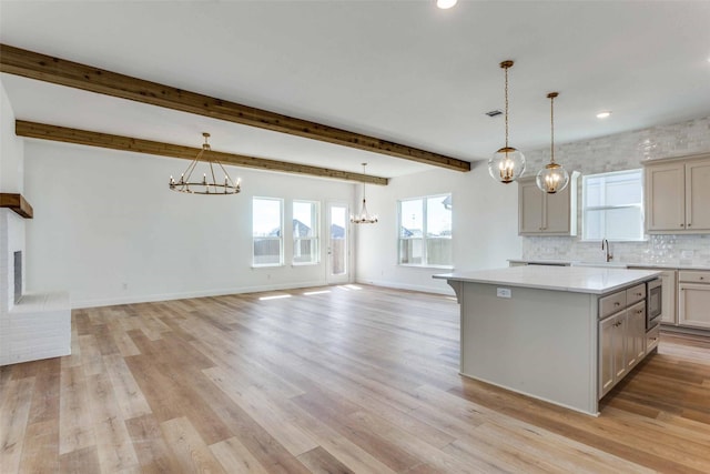 kitchen featuring light wood-style flooring, a kitchen island, a chandelier, and beam ceiling