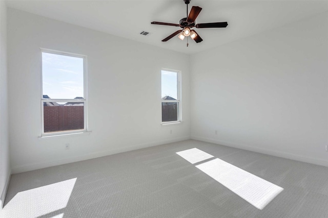 spare room featuring visible vents, ceiling fan, light carpet, and baseboards