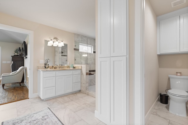 bathroom with tile patterned floors, vanity, toilet, and tiled shower