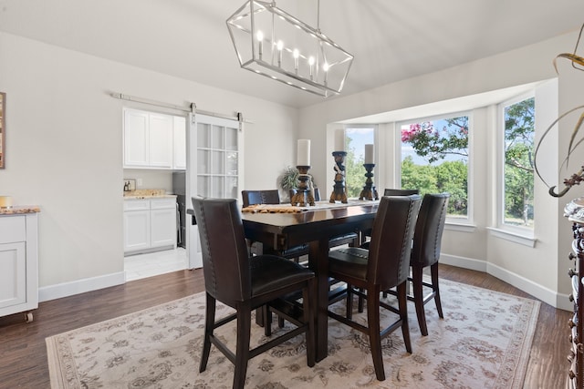 dining area featuring a notable chandelier, a barn door, and hardwood / wood-style flooring