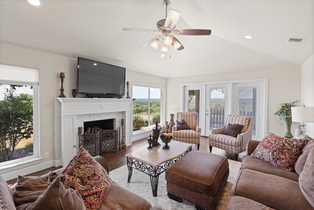 living room featuring lofted ceiling, a brick fireplace, wood-type flooring, ceiling fan, and french doors