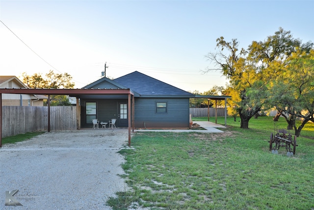 back house at dusk with a lawn and a patio area