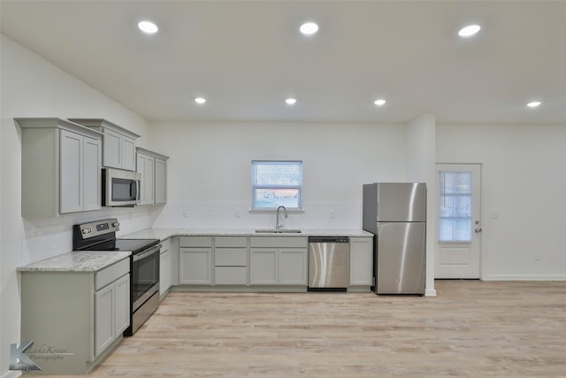 kitchen featuring light hardwood / wood-style floors, appliances with stainless steel finishes, sink, and gray cabinetry