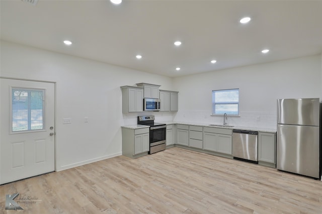 kitchen featuring gray cabinetry, light wood-type flooring, appliances with stainless steel finishes, and sink