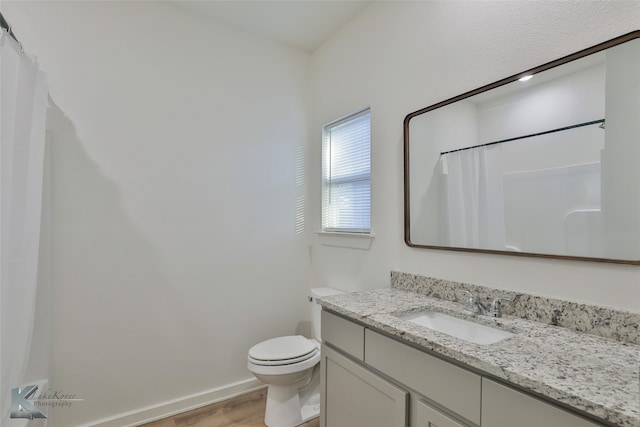 bathroom featuring hardwood / wood-style floors, walk in shower, vanity, and toilet