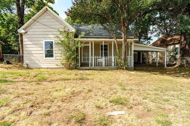 back of property featuring covered porch and a yard