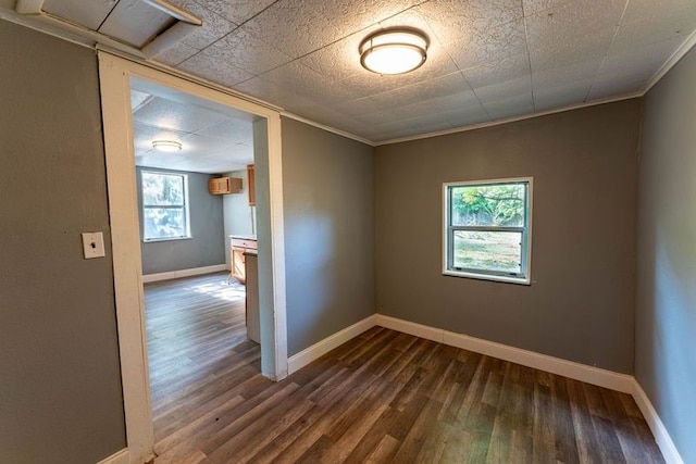 empty room with crown molding, dark hardwood / wood-style floors, a wealth of natural light, and a wall mounted AC