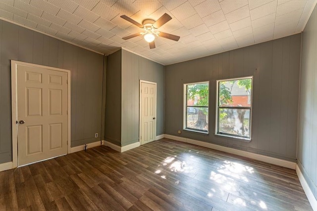 spare room with wood walls, dark hardwood / wood-style floors, crown molding, and ceiling fan