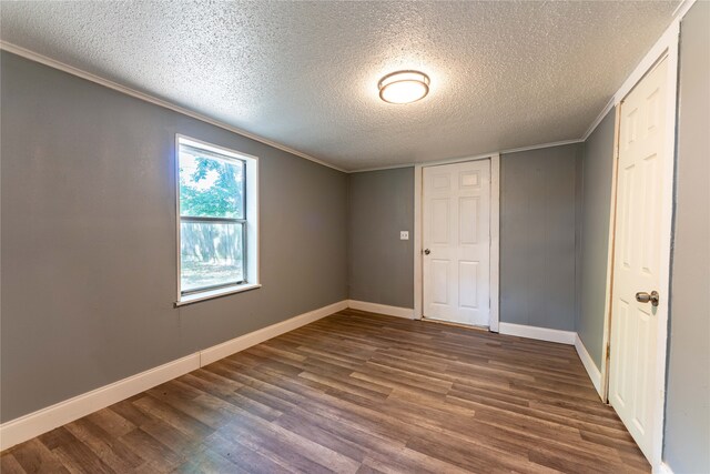 unfurnished bedroom featuring a textured ceiling, ornamental molding, a closet, and wood-type flooring